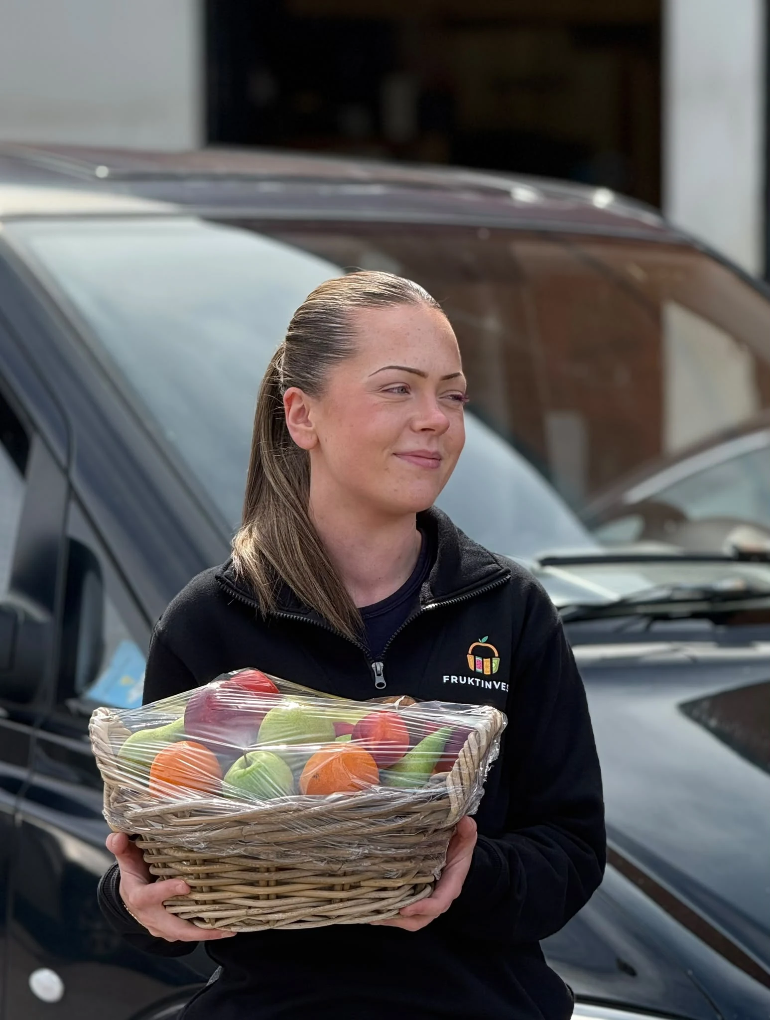 Fruktinvest levererar en fruktkorg vid bilen